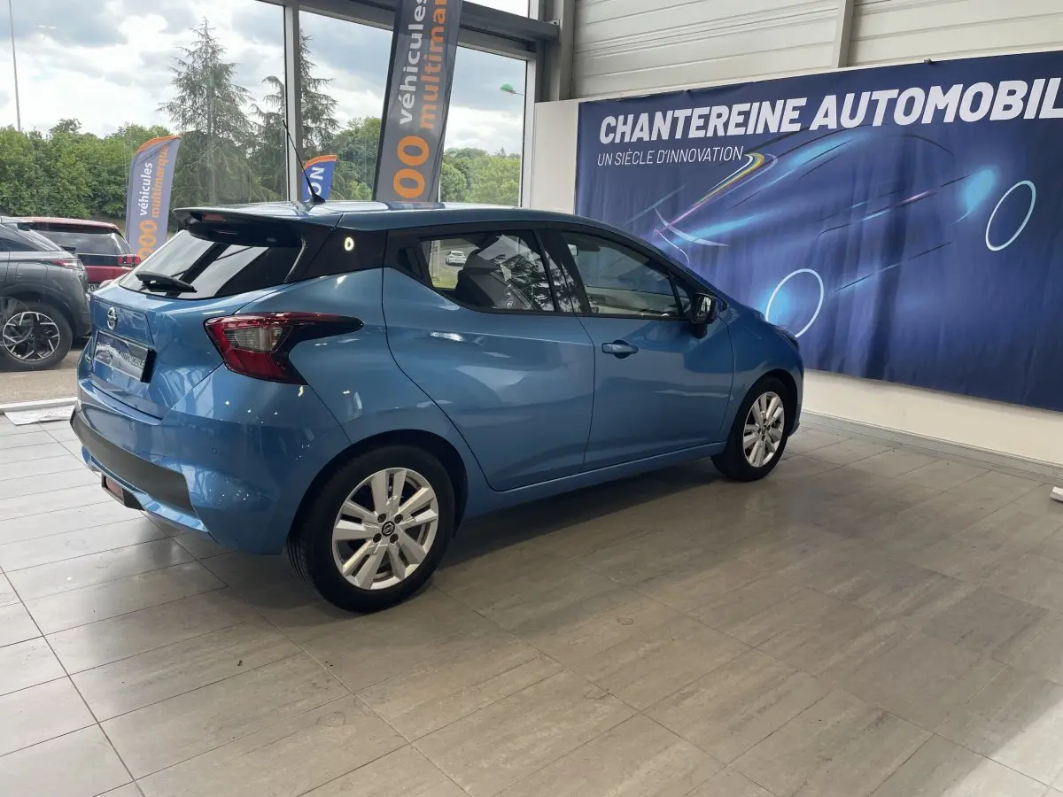 Nissan Micra IG-T 100 N-Connecta bleu vue 3/4 arrière droit en intérieur, avec jantes alliage et vitres teintées.