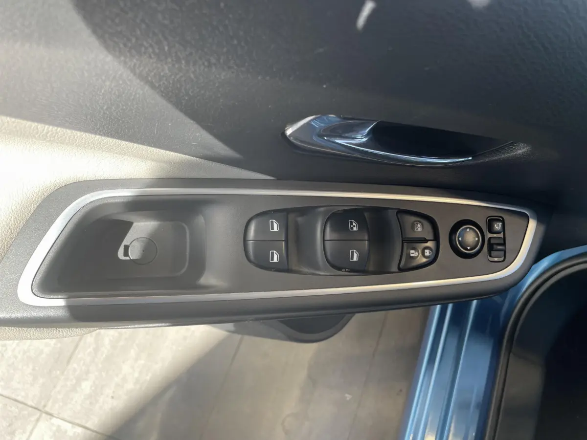 Vue rapprochée du panneau de commandes des vitres et rétroviseurs côté conducteur d'une Nissan Micra bleu 2020.