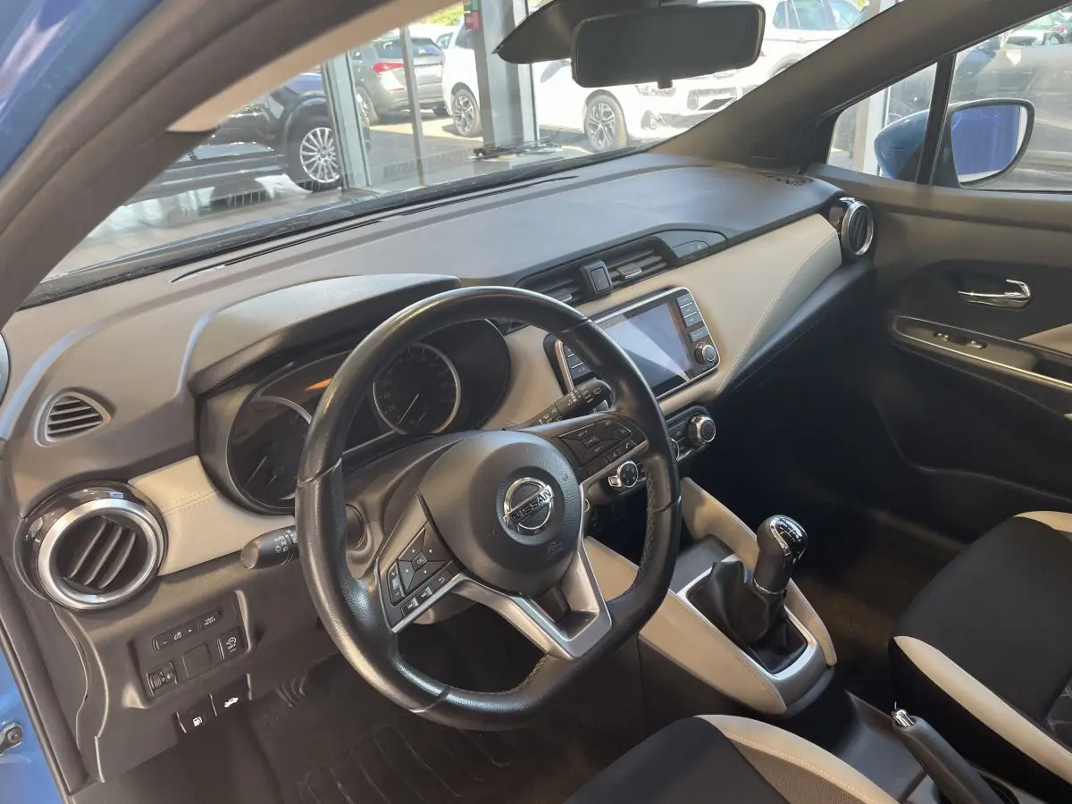 Vue intérieure côté conducteur de la Nissan Micra bleu 2020, volant cuir multifonctions et écran tactile central visible.