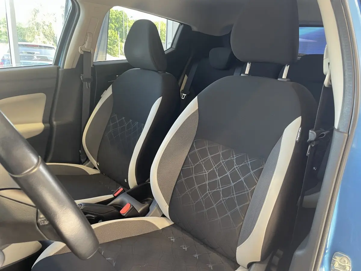 Vue intérieure côté conducteur de la Nissan Micra IG-T 100 N-Connecta bleue, sièges avant noirs avec surpiqûres grises.