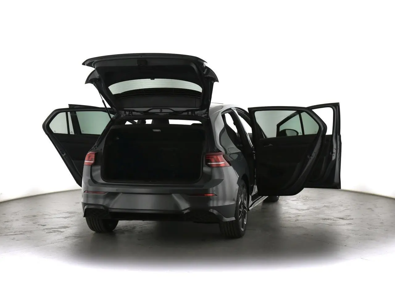 Volkswagen Golf VIII gris dauphin vue arrière avec portes et coffre ouverts dans un studio lumineux.