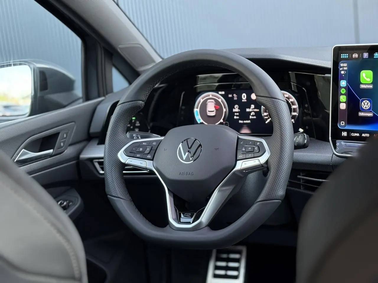 Vue intérieure centrée sur le volant sport Volkswagen Golf VIII avec tableau de bord numérique et écran tactile.