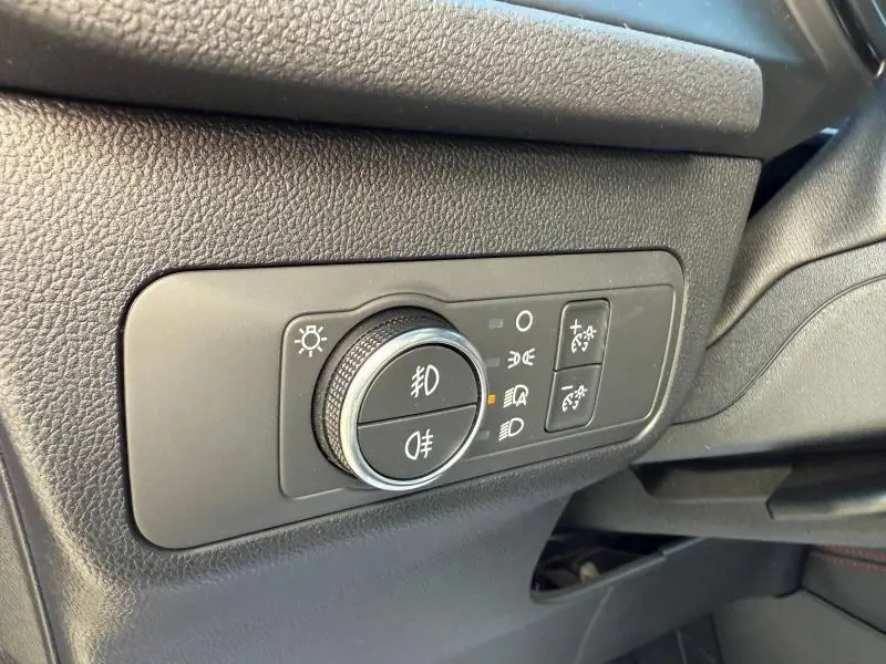 Gros plan sur la commande d’éclairage noire avec molette chromée du tableau de bord côté gauche du Ford Kuga noir Agate Métallisée 2024.