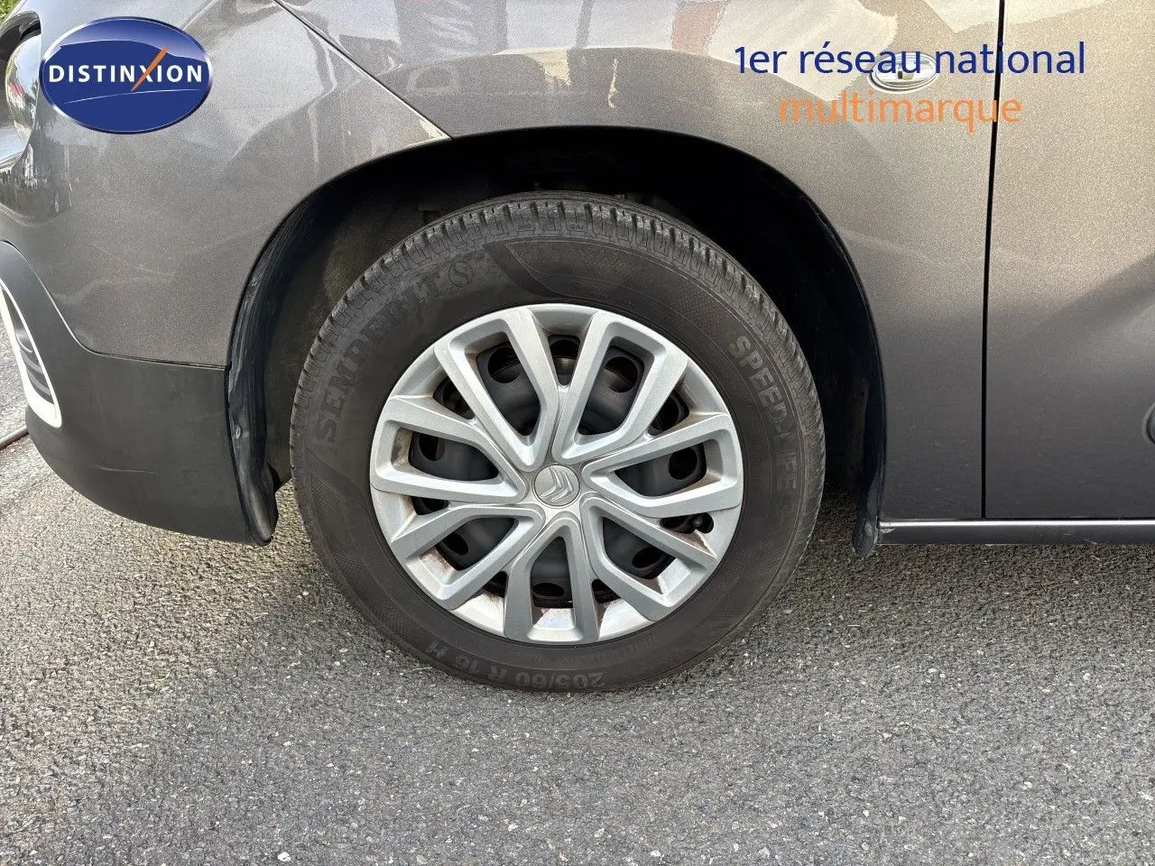Gros plan sur la roue avant gauche d'une Citroën Berlingo Multispace gris platinium, mettant en valeur la jante et la carrosserie.