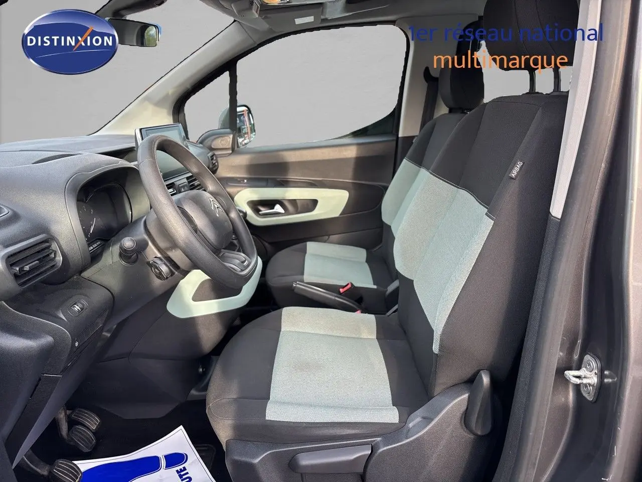 Vue intérieure côté conducteur du Citroën Berlingo Multispace gris platinium, sièges bicolores noirs et gris avec volant visible.