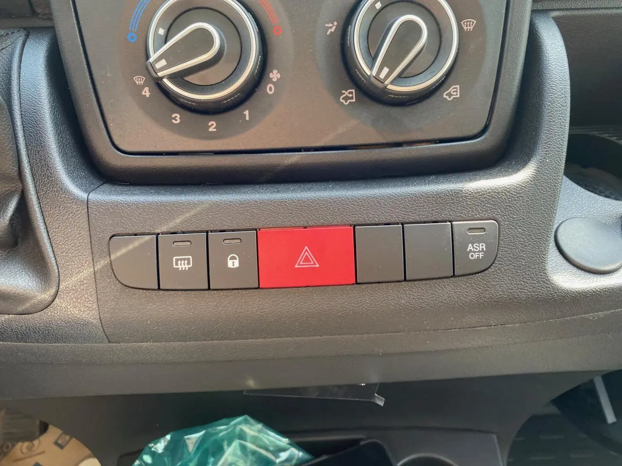 Vue rapprochée des commandes de climatisation et des boutons de sécurité sur le tableau de bord du Citroën Jumper blanc 2023.