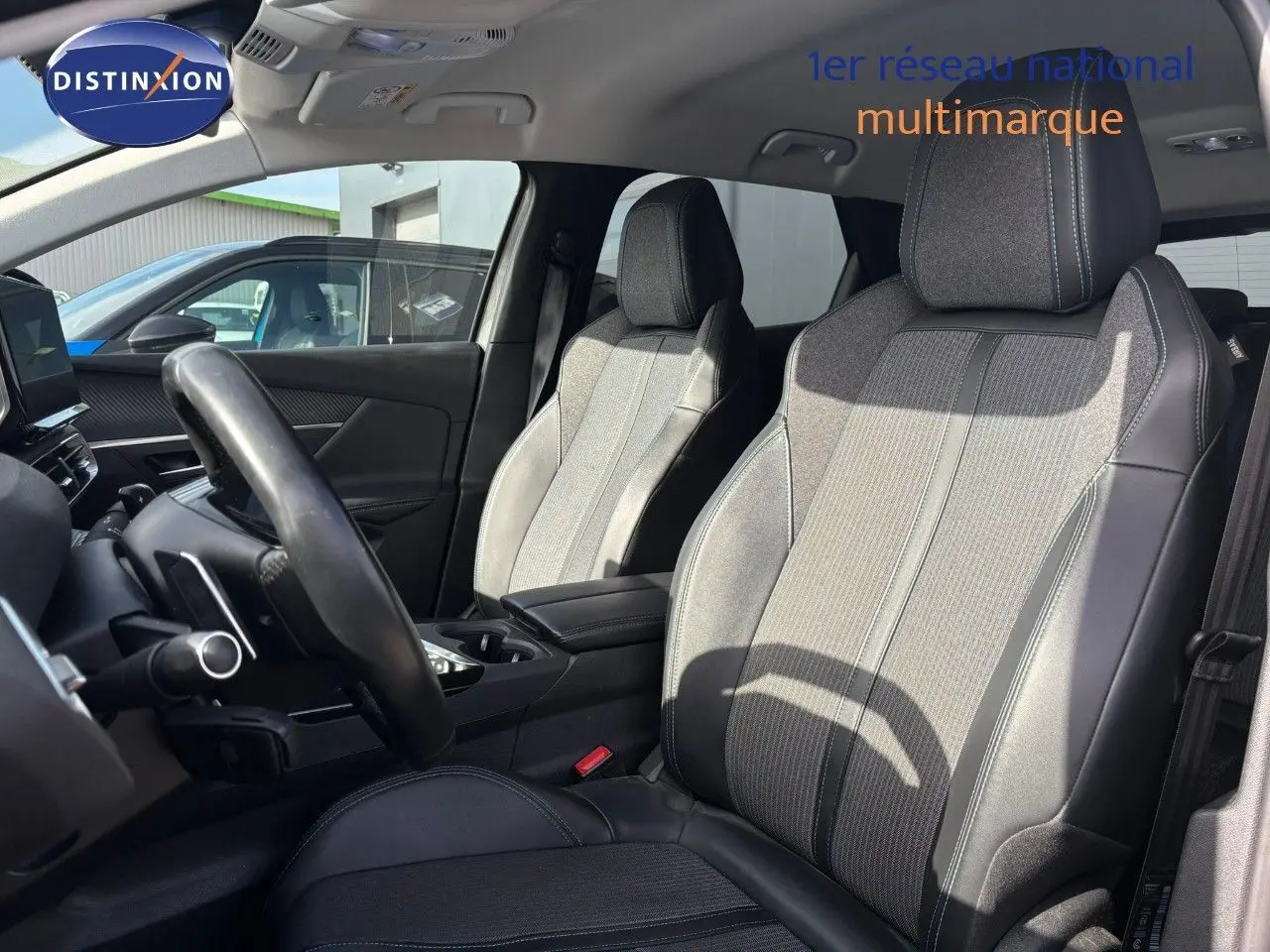 Intérieur du Peugeot 3008 hybride 2022, vue côté conducteur sur sièges en tissu et cuir gris avec volant noir.