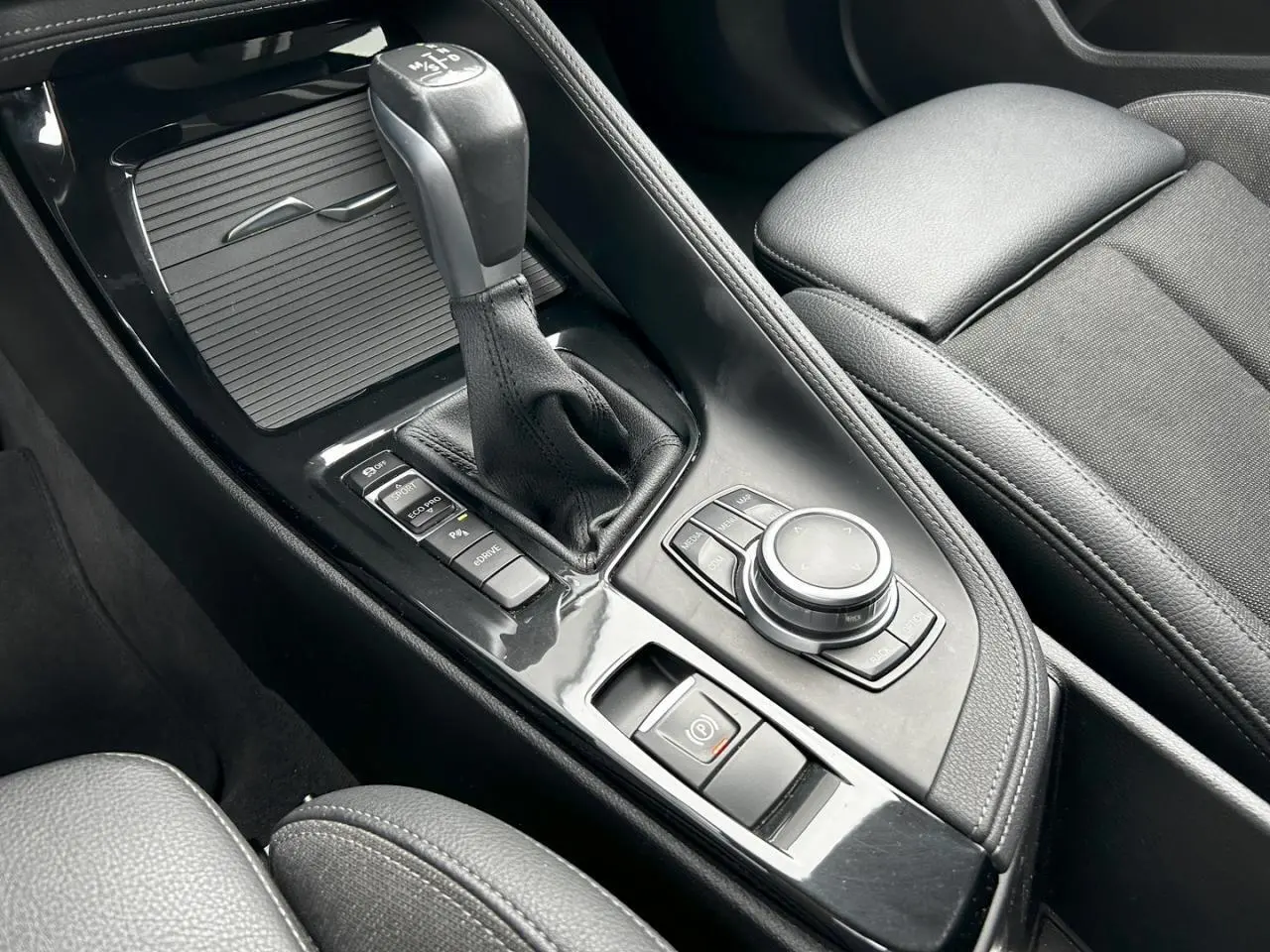 Gros plan sur la console centrale noire du BMW X2 F39 avec levier de vitesses automatique et commandes multimédia.