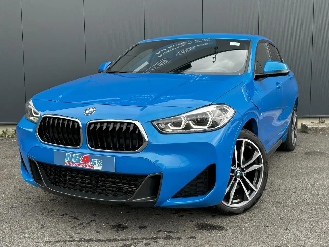 BMW X2 bleu Misano en vue 3/4 avant droit, avec calandre noire et jantes alliage bicolores 19 pouces.