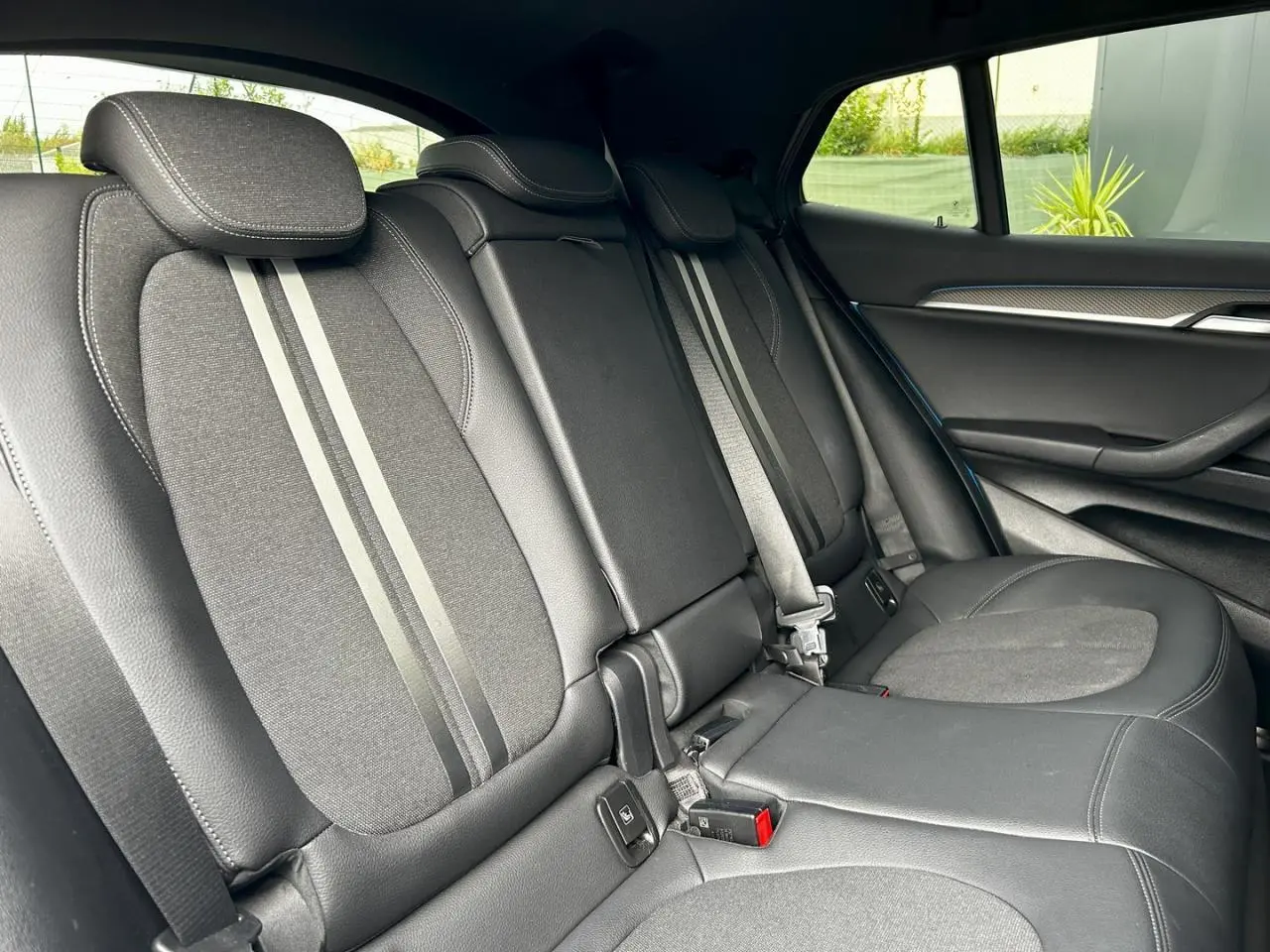 Vue latérale droite de l'intérieur arrière d'une BMW X2 2021 avec sièges noirs en cuir et tissu, finition M Sport.