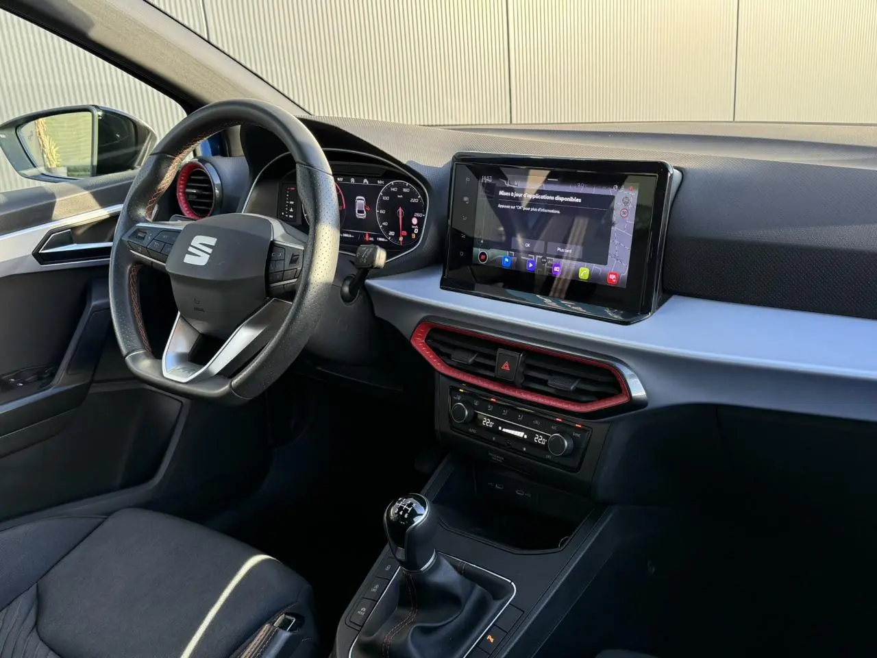 Intérieur avant droit de la SEAT Ibiza TSI 115 FR 2025 avec tableau de bord noir et touches rouges, écran tactile et boîte manuelle.