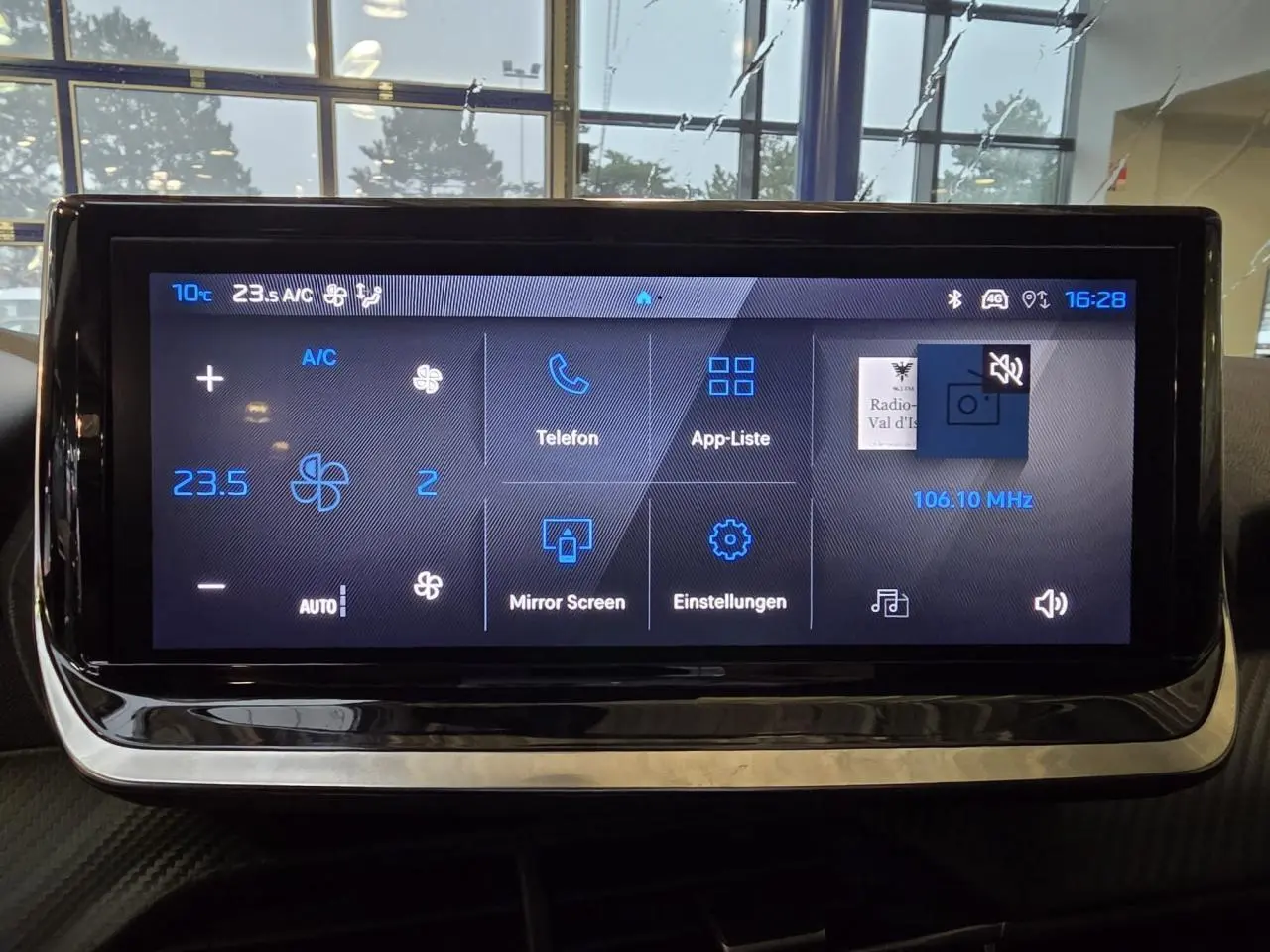 Écran tactile central du tableau de bord du Peugeot 208 1.2i Hybrid en intérieur, affichage des commandes climatisation et multimédia.