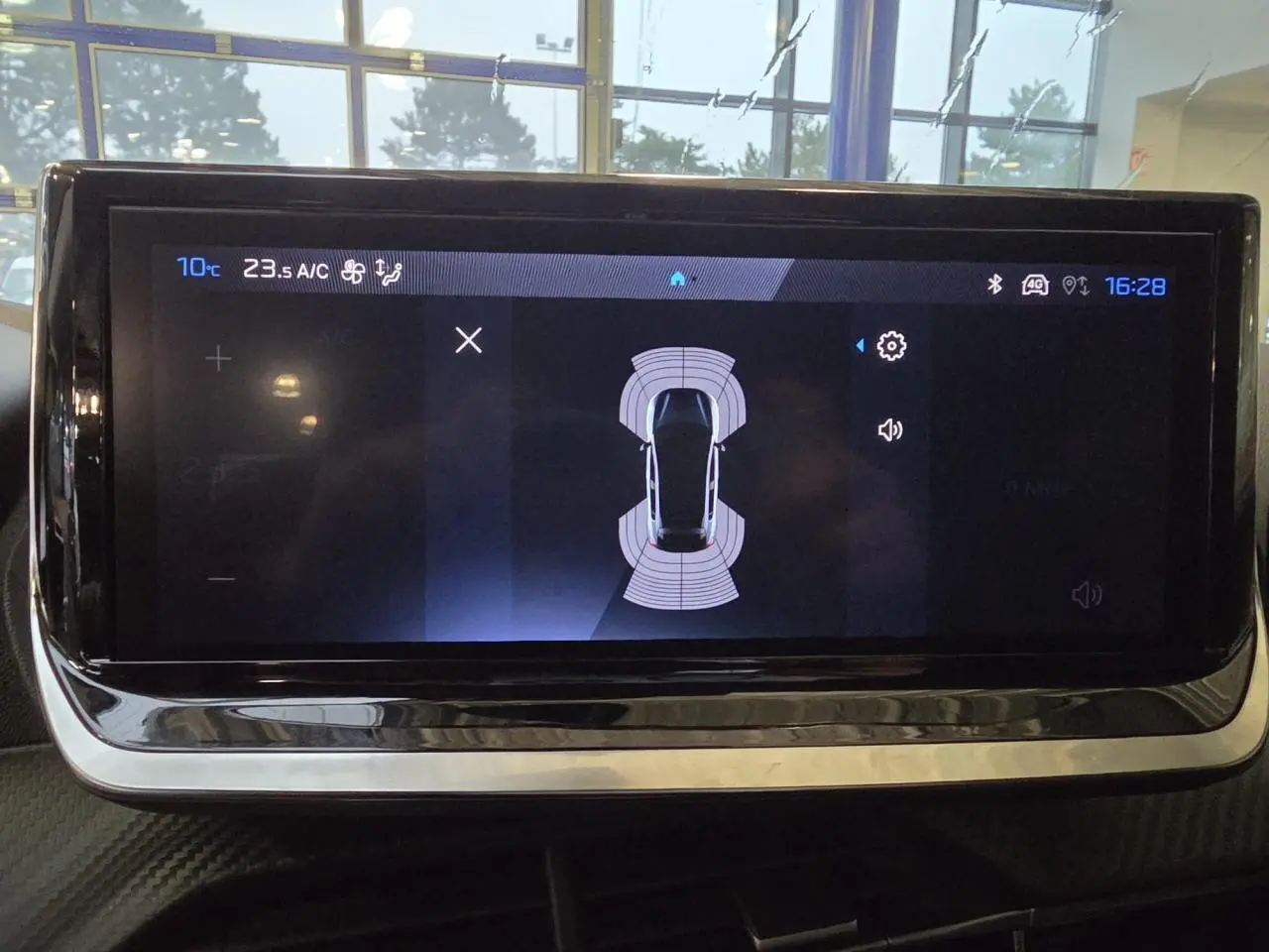 Écran tactile central du Peugeot 208 2025 affichant l'aide au stationnement avec vue de dessus du véhicule.