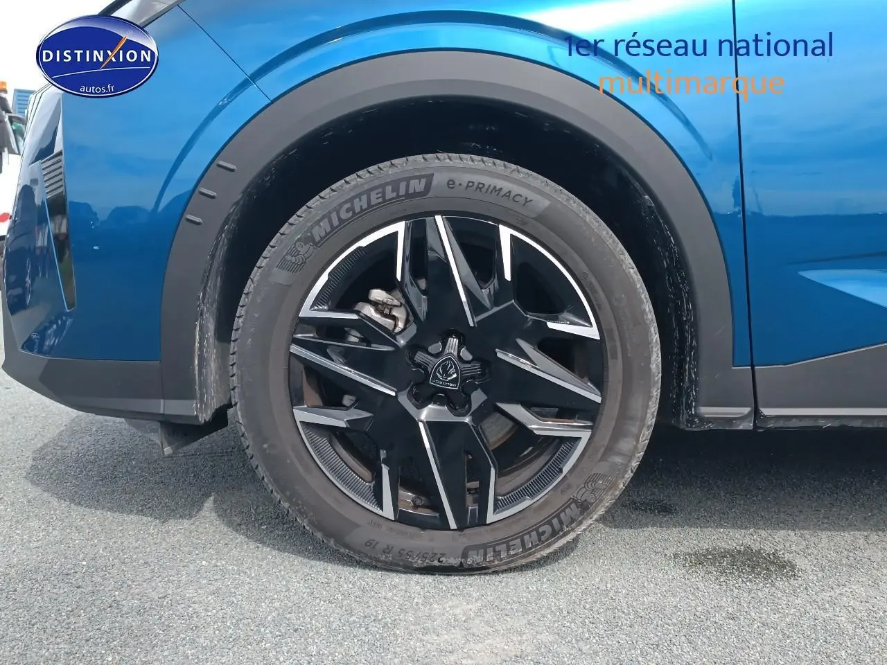 Gros plan sur la roue avant gauche d'un Peugeot 5008 Hybrid 145 allure bleu, jante alu noire et argentée.