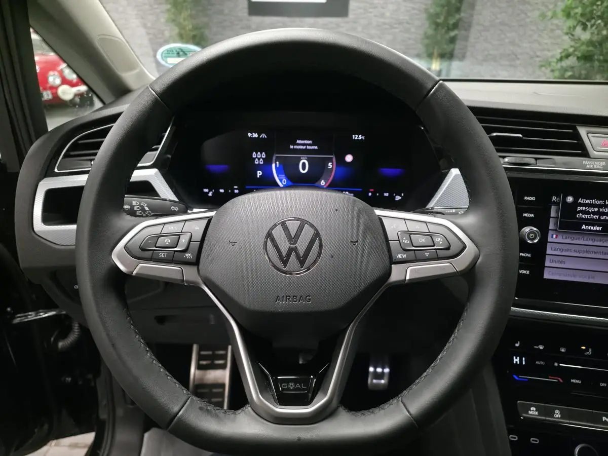 Vue rapprochée du volant cuir multifonction noir du Volkswagen Touran 2025 avec badge GOAL et tableau de bord digital.