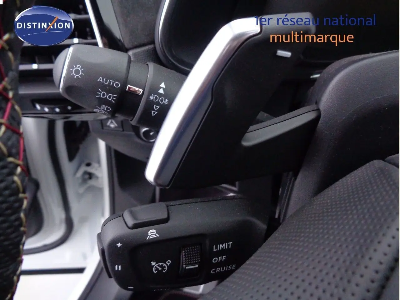 Gros plan sur les commandes au volant du DS7 Crossback blanc nacré, mettant en valeur les réglages du régulateur de vitesse.