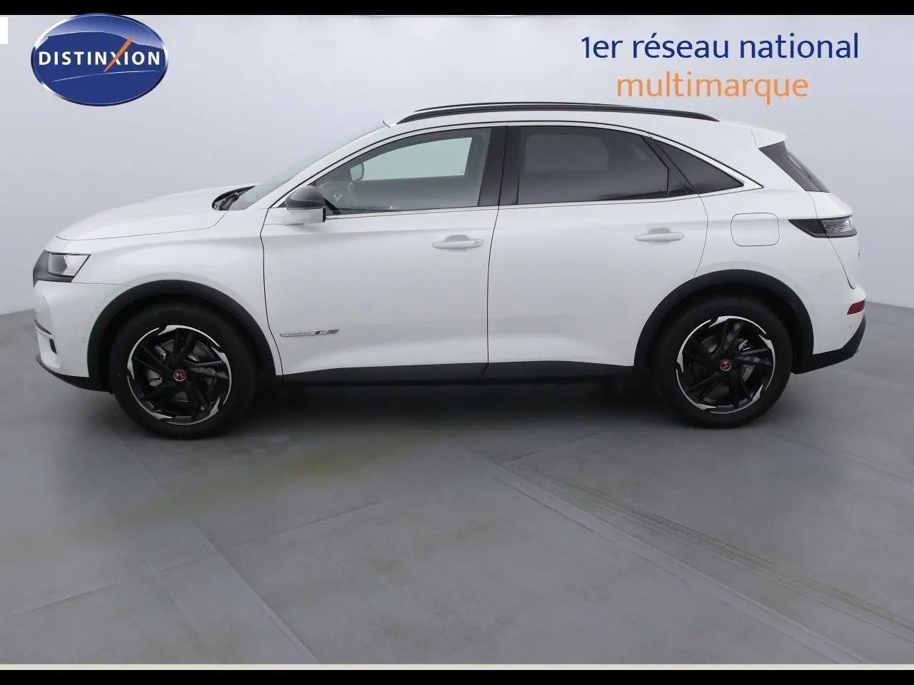 Vue latérale droite d'un DS7 Crossback E-TENSE 300CH blanc nacré métallisé avec jantes noires en intérieur studio.