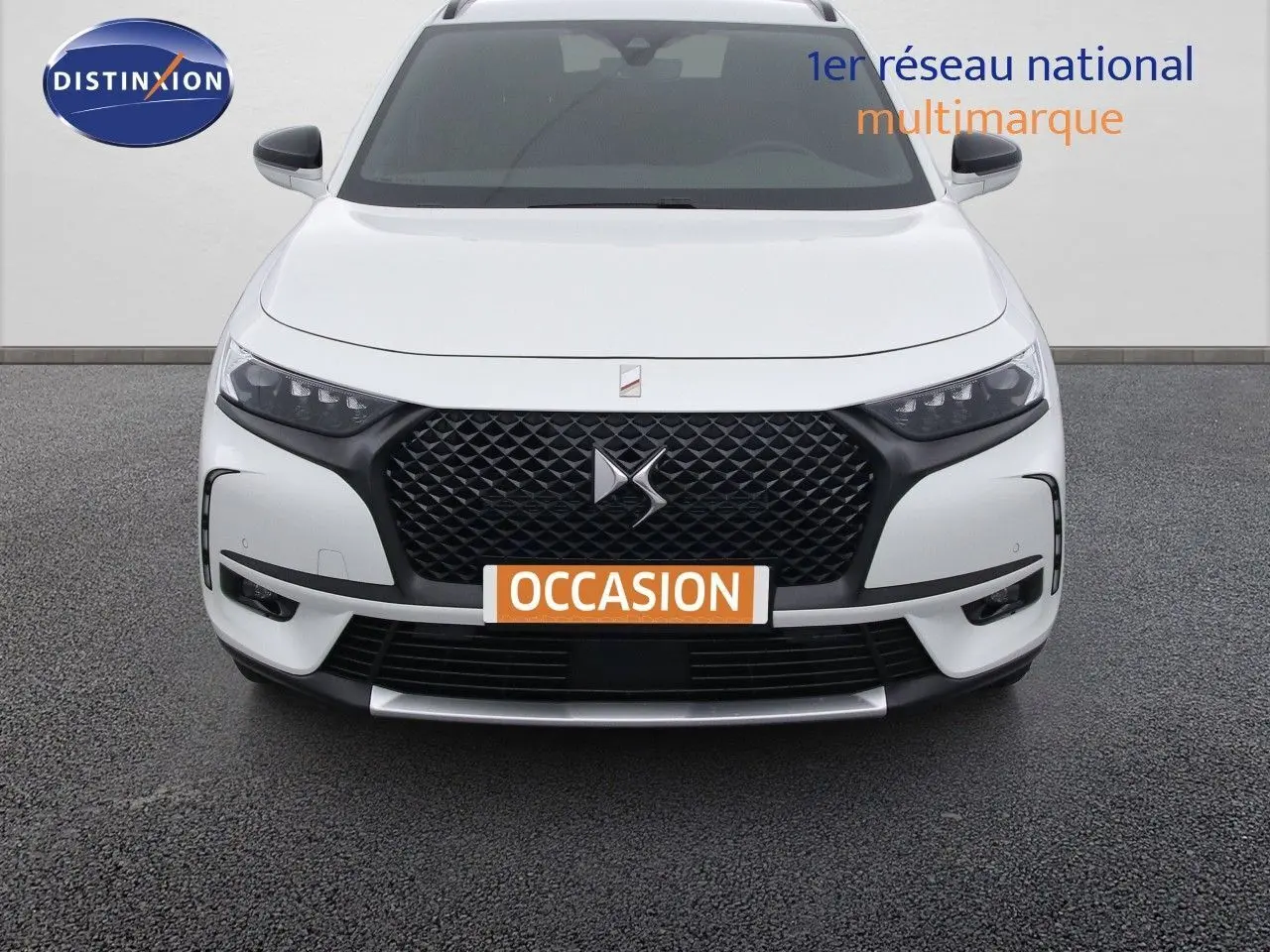 Vue frontale d'un DS7 Crossback E-TENSE blanc nacré avec calandre noire et phares LED distinctifs.