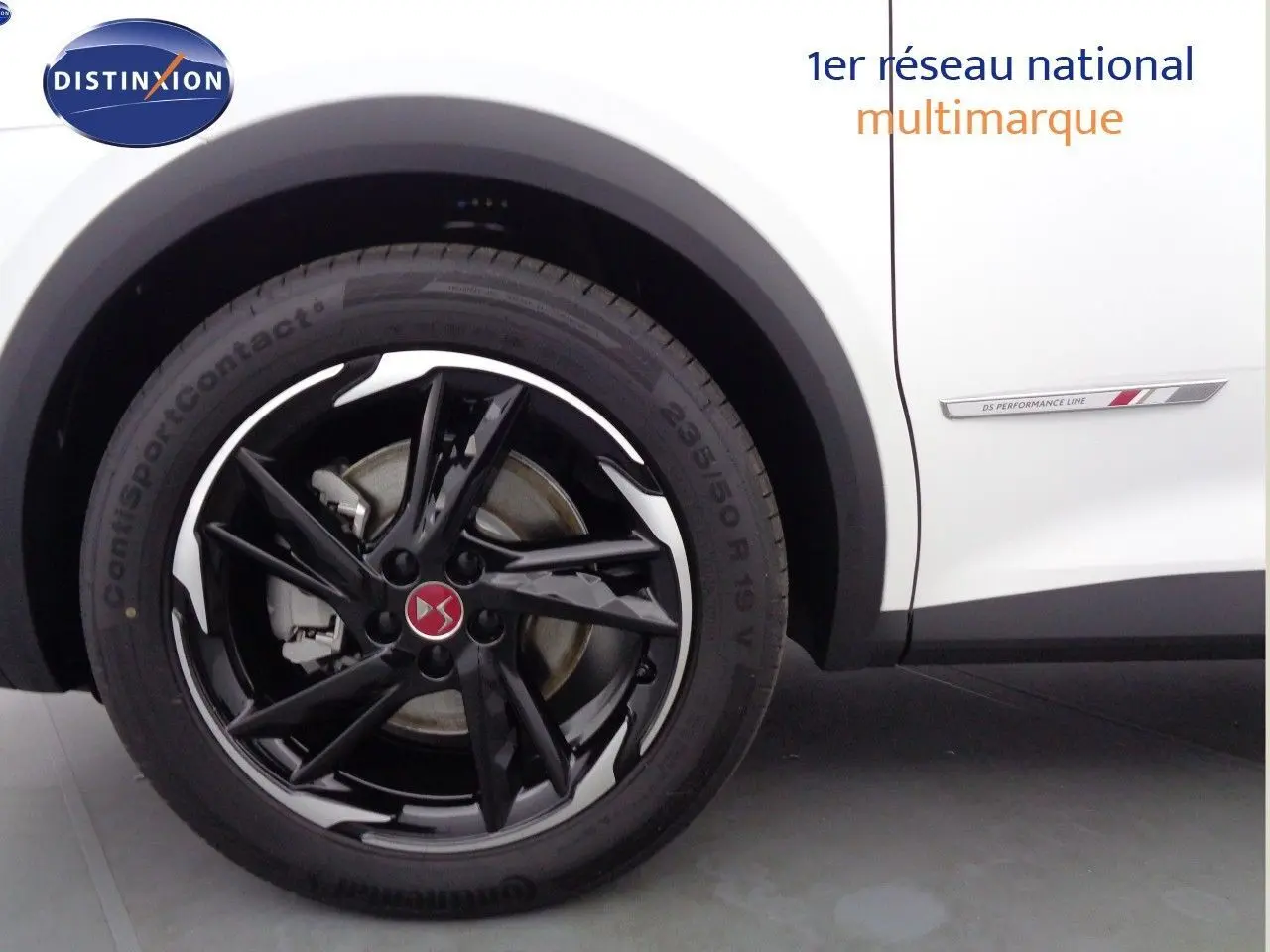 Gros plan sur la roue avant gauche noire brillante et la carrosserie blanche nacrée du DS7 Crossback E-TENSE 300CH PERF LINE +