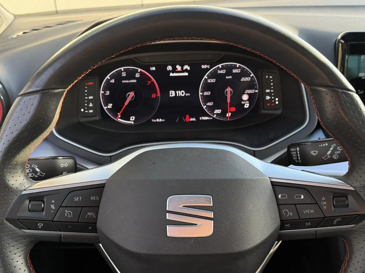 Vue rapprochée du volant cuir noir avec surpiqûres rouges et tableau de bord digital de la SEAT IBIZA TSI 115 FR 2025.