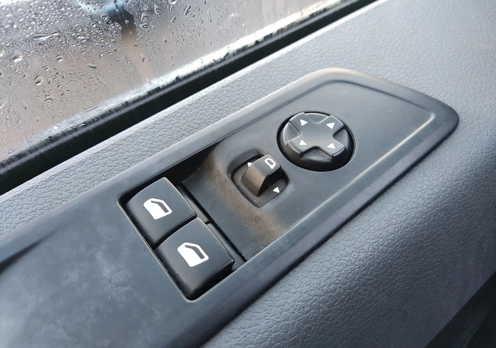 Gros plan sur les commandes de lève-vitres et réglage des rétroviseurs côté conducteur du Citroën Jumpy blanc de 2021.