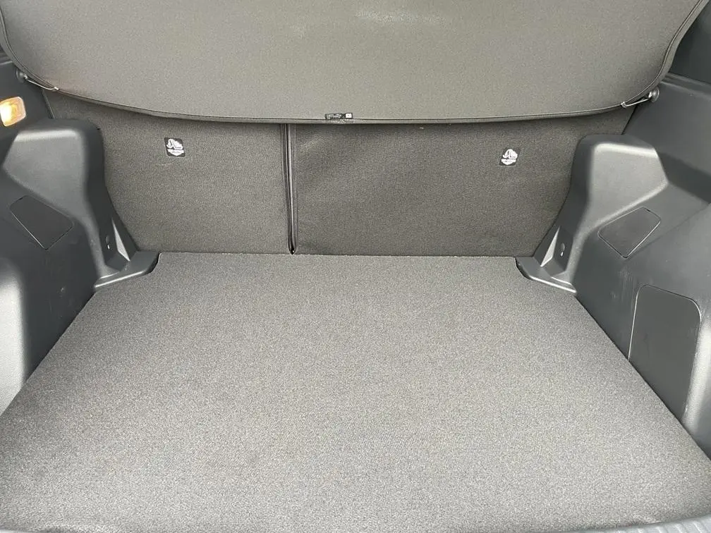 Coffre ouvert de la Toyota Yaris Cross gris clair, montrant l'espace de chargement et la finition intérieure en tissu noir.