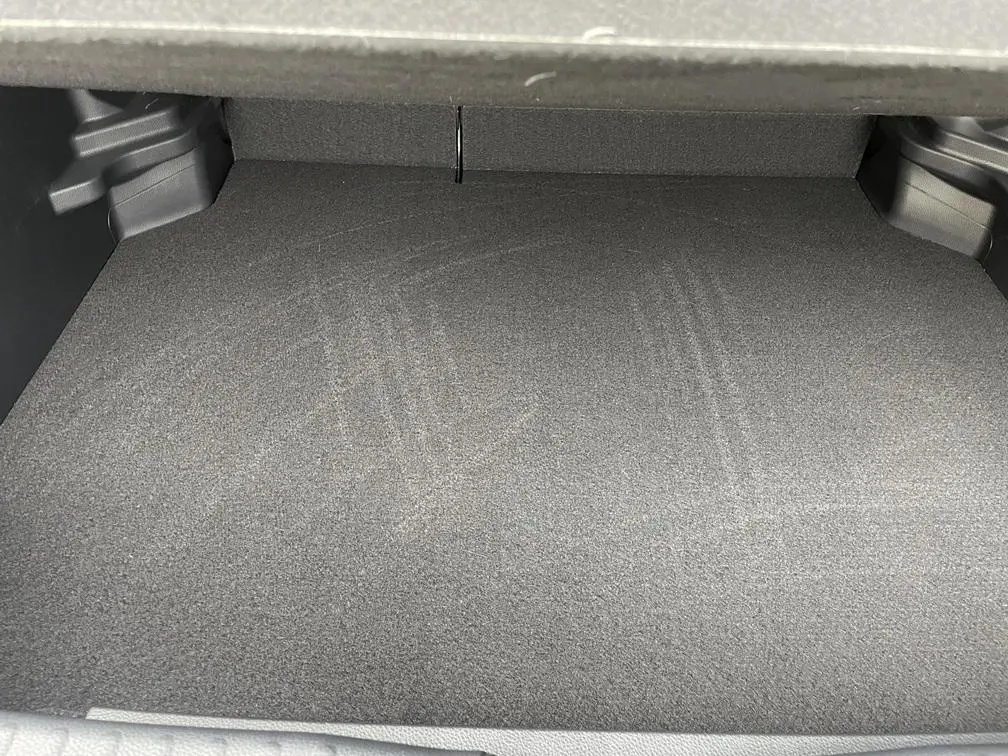 Coffre vide de la Toyota Yaris Cross 1.5 Hybrid 130h, vue intérieure, revêtement gris foncé uniforme.