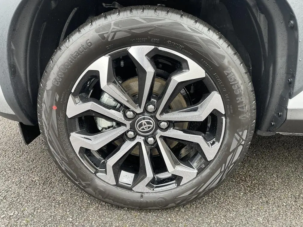 Gros plan sur la roue avant droite de la Toyota Yaris Cross gris clair avec jante alliage noire et argentée design moderne.