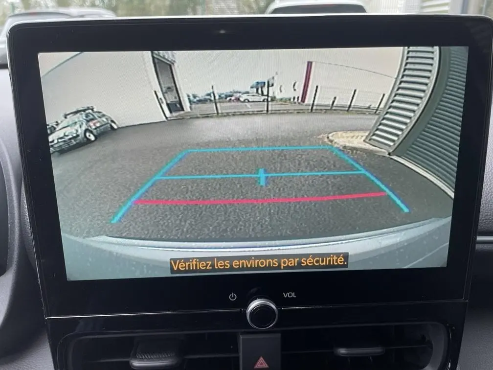 Vue caméra de recul du Toyota Yaris Cross gris clair montrant l’arrière avec lignes de guidage bleues et rouges.