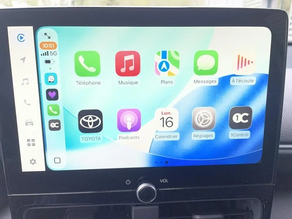 Écran tactile central affichant Apple CarPlay dans une Toyota Yaris Cross 1.5 Hybrid gris clair, vue intérieure frontale.