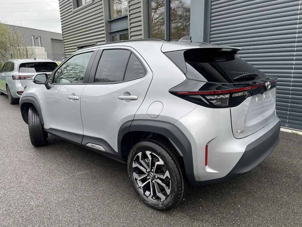 Vue 3/4 arrière droit d'une Toyota Yaris Cross gris clair avec jantes alliage et détails noirs sur le hayon.