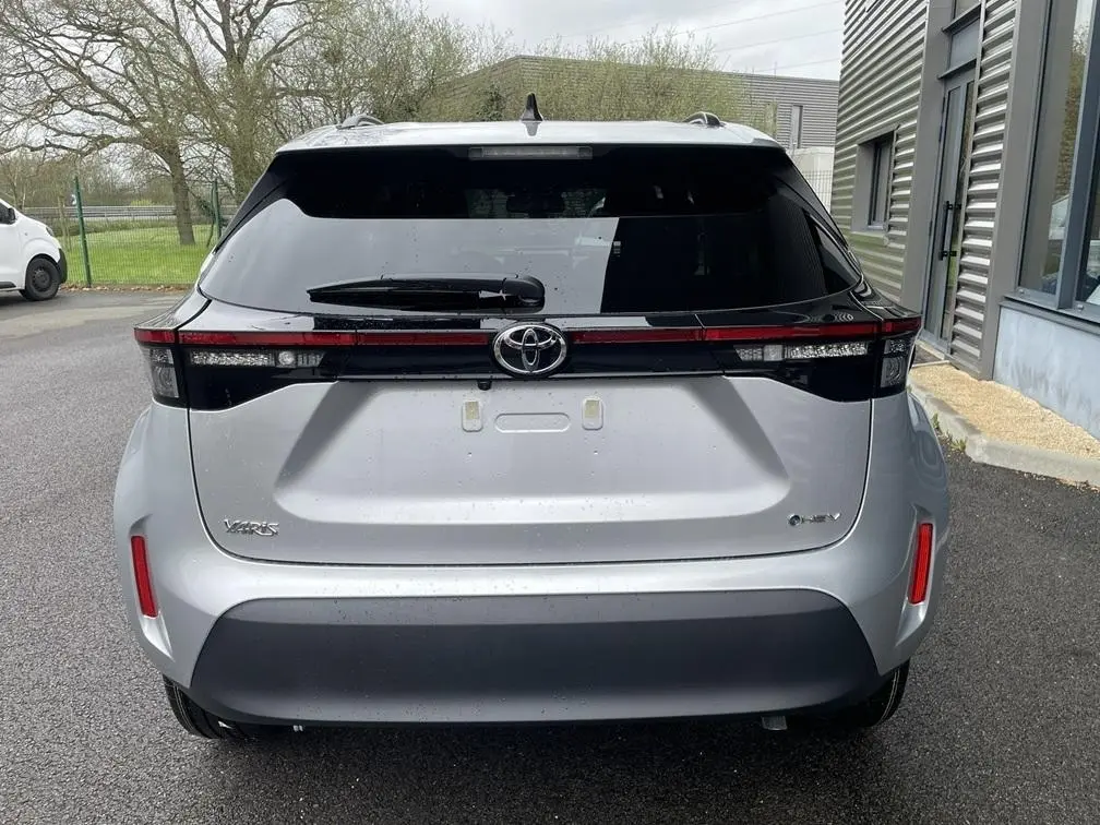 Vue arrière de la Toyota Yaris Cross gris clair 2026 avec feux arrière en bandeau et logo Toyota central.