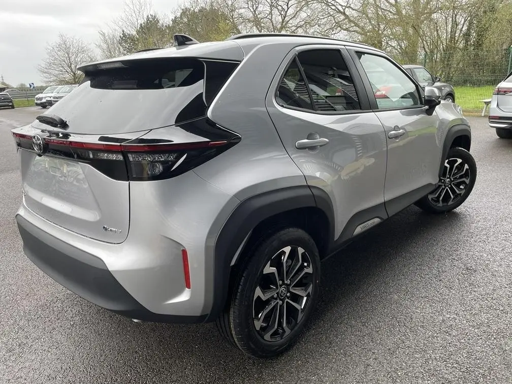 Vue 3/4 arrière droite d'une Toyota Yaris Cross gris clair avec jantes noires et toit noir contrasté.