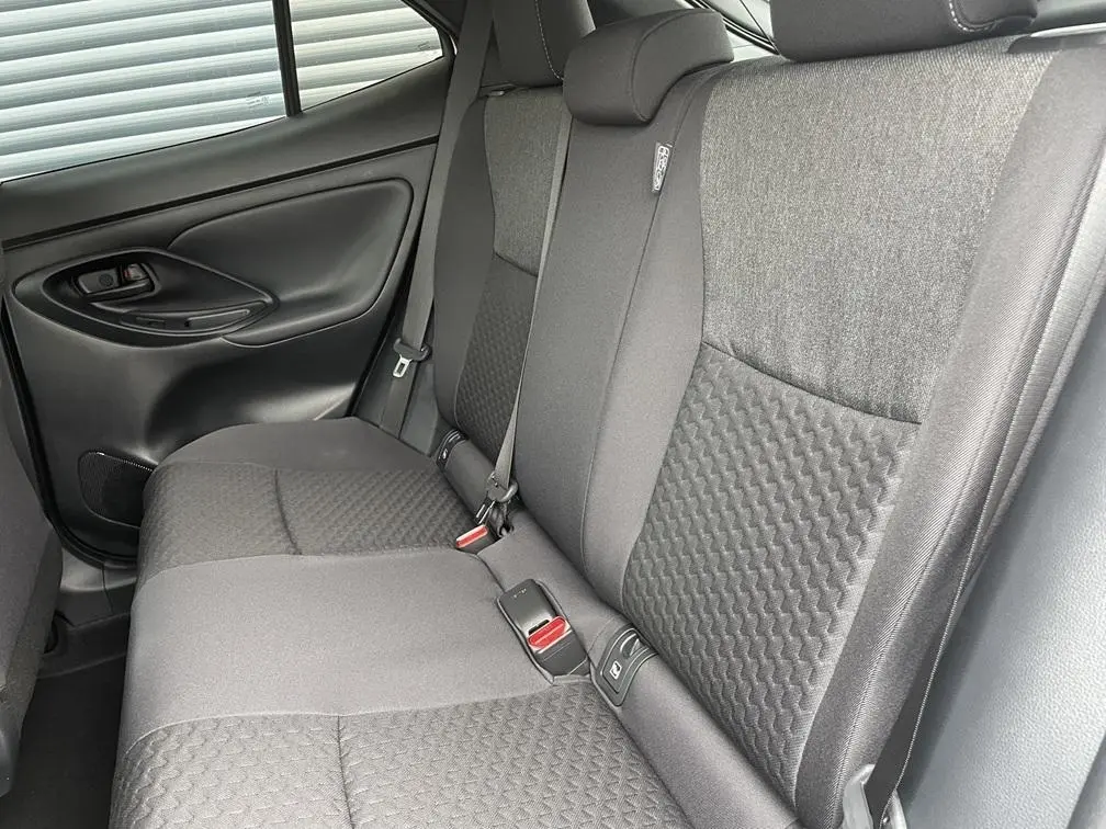 Vue intérieure côté gauche des sièges arrière gris foncé avec ceintures et texture en relief de la Toyota Yaris Cross 2026.