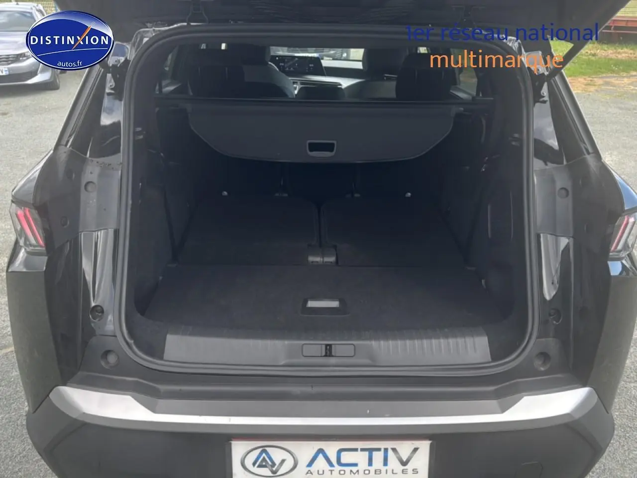 Coffre ouvert en vue arrière d’un Peugeot 5008 noir, banquette arrière rabattue et cache-bagages déployé.