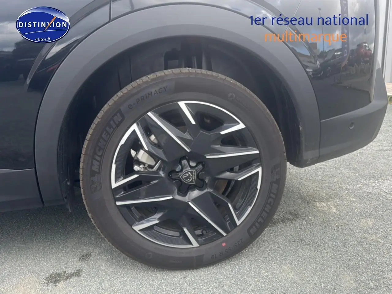 Gros plan sur la roue avant droite noire du Peugeot 5008 Hybrid 145 allure e-dcs6 avec jante alu bicolore.