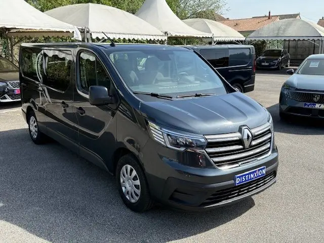 Renault Trafic Combi L2 gris comète en 3/4 avant droit, fourgon 9 places avec calandre chromée et phares LED.