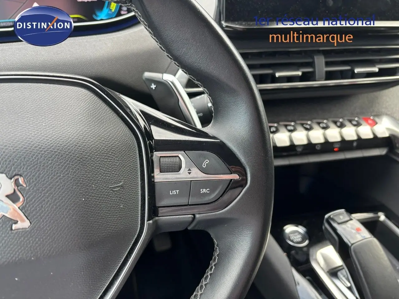 Gros plan sur le volant cuir noir du Peugeot 3008 hybride 2022 avec commandes intégrées et levier de vitesse visible.