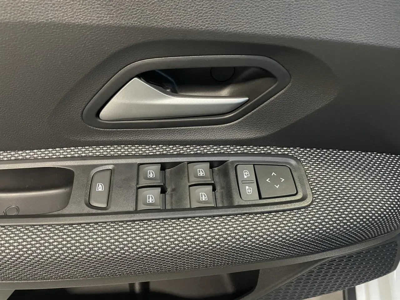 Détail de la commande des vitres électriques et poignée intérieure côté gauche d’une Dacia Sandero Stepway blanc glacier.