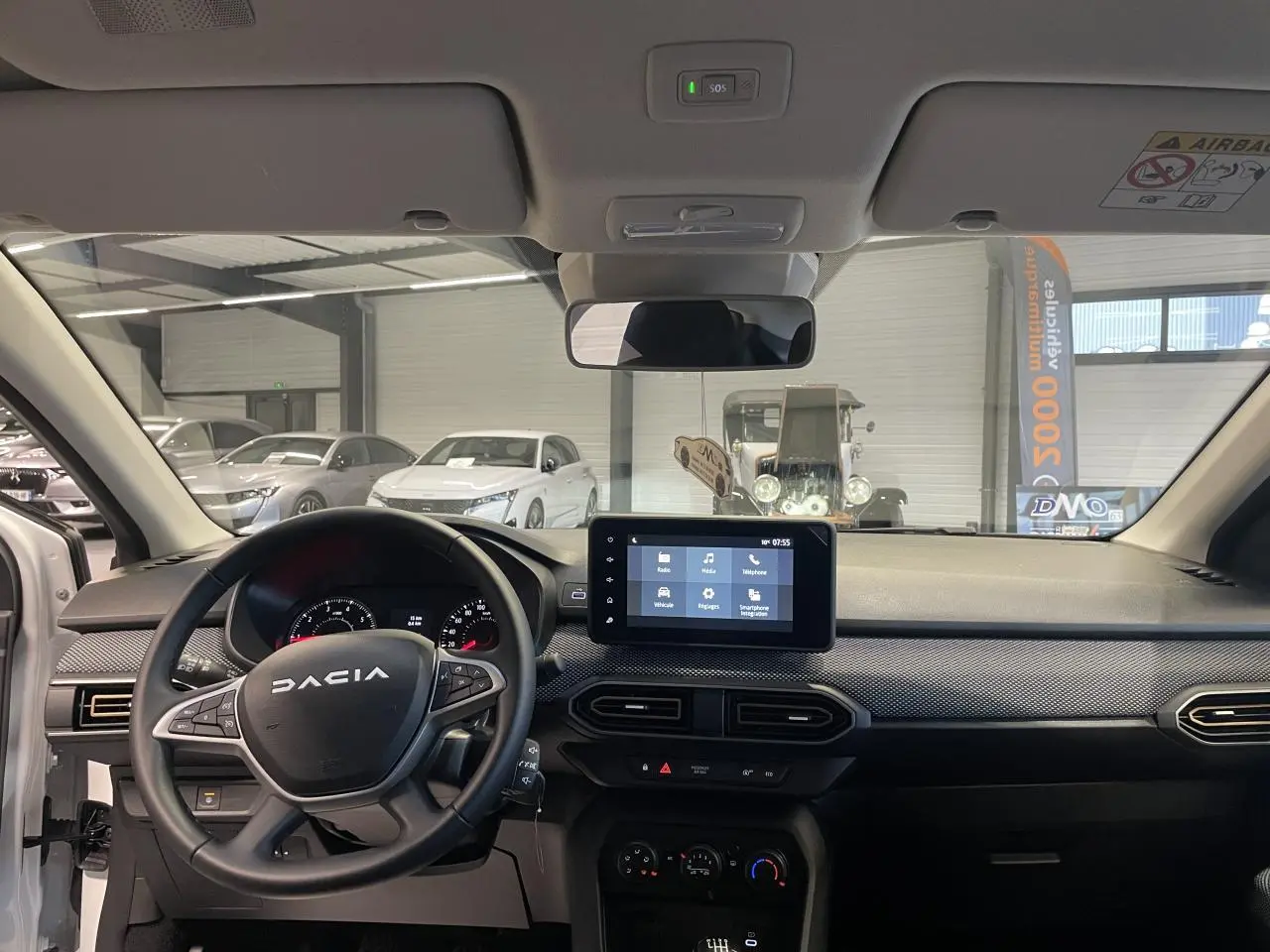 Vue intérieure avant de la Dacia Sandero TCe 90 Stepway 2025, tableau de bord noir avec écran tactile central.