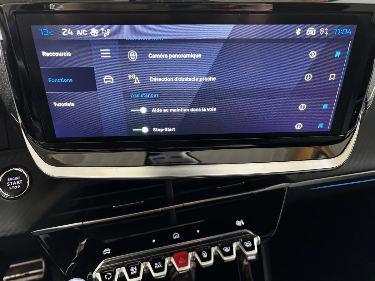 Écran tactile central affichant les aides à la conduite sur Peugeot 208 Hybrid 110 e-DCS6 GT gris clair, vue intérieure frontale.