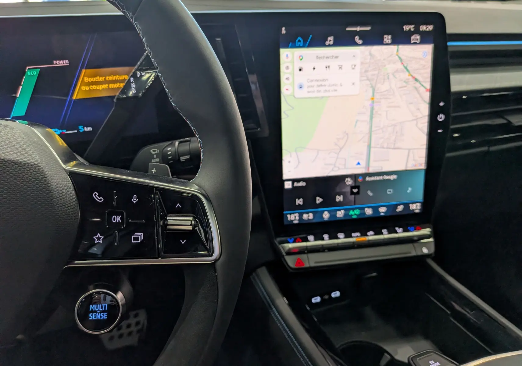 Vue intérieure rapprochée du volant et de l’écran tactile central du Renault Rafale gris, mettant en valeur les commandes et la navigation.