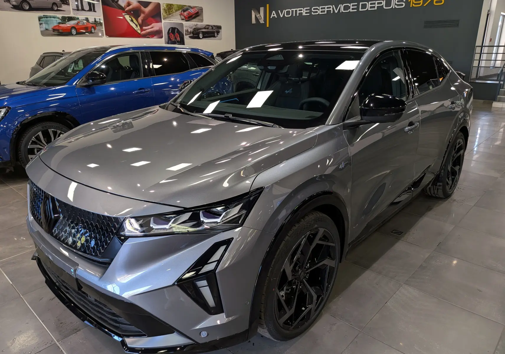 Renault Rafale gris schiste en 3/4 avant droit, avec jantes noires et détails noirs brillants, en showroom intérieur.