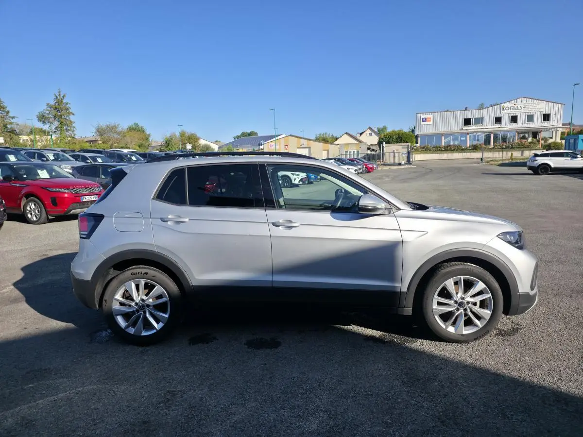 Vue latérale droite d'un Volkswagen T-Cross gris métallisé 2025 avec jantes alliage 17 pouces sur parking extérieur.
