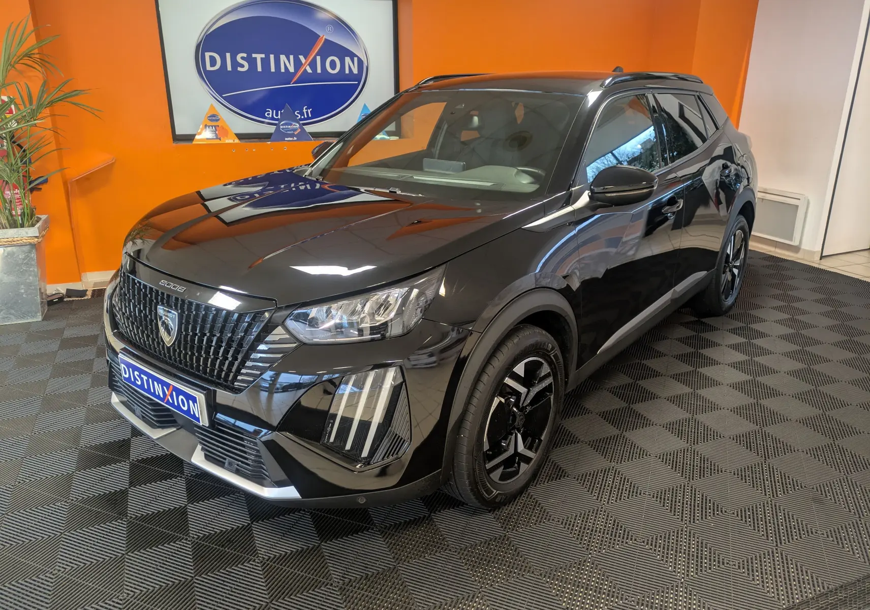 Peugeot 2008 noir perla en 3/4 avant droit, avec jantes alliage 17'' et barres de toit noir brillant, en intérieur showroom.