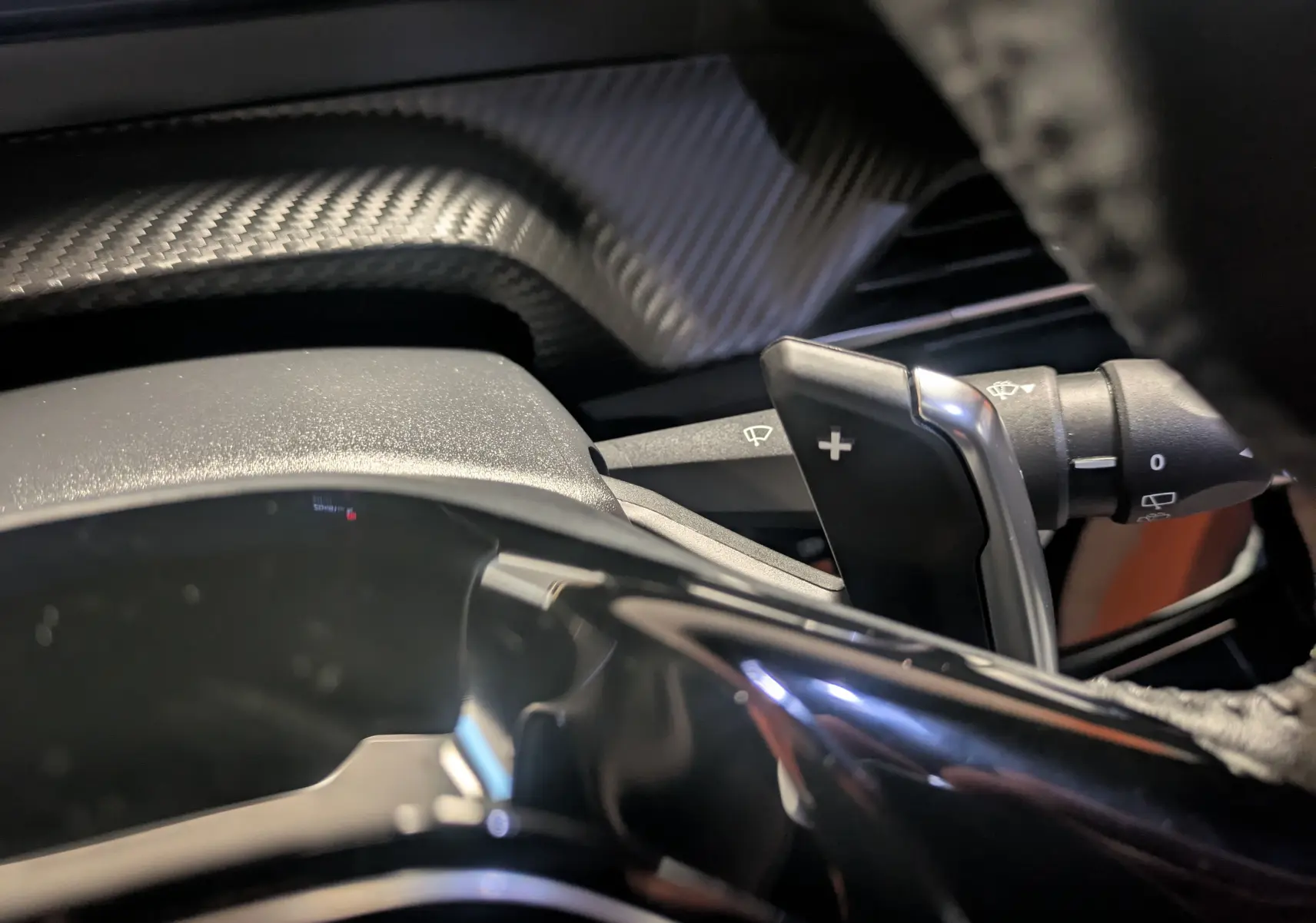 Gros plan sur la palette de changement de vitesse + côté droit du volant avec habillage carbone du Peugeot 2008 noir perla 2024.