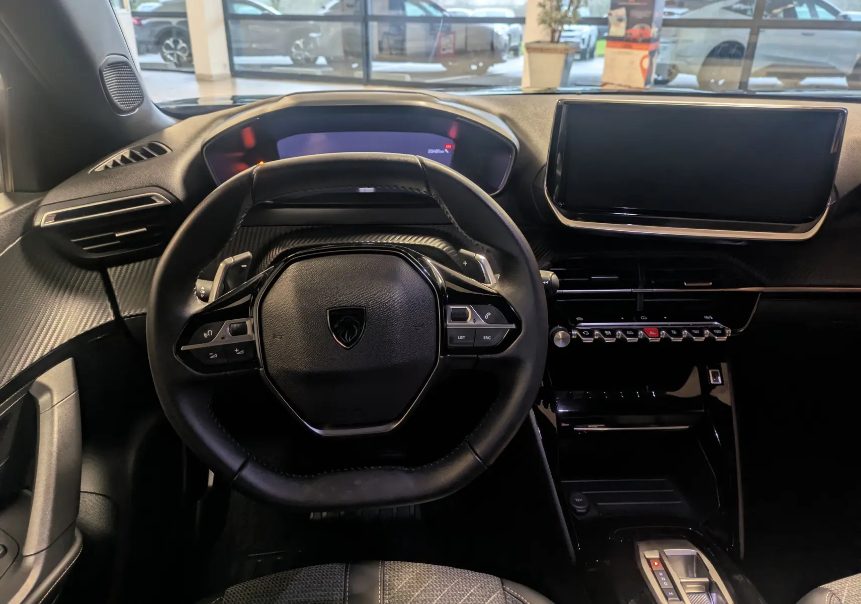 Vue intérieure du tableau de bord du Peugeot 2008 noir Perla 2024, avec volant compact et écran tactile central.