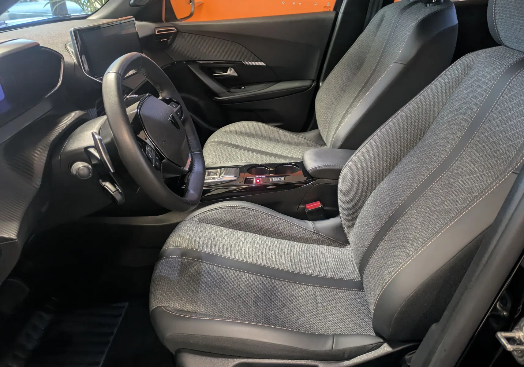 Intérieur avant droit du Peugeot 2008 noir Perla 2024, sièges tissu et cuir, tableau de bord avec écran tactile 10 pouces.