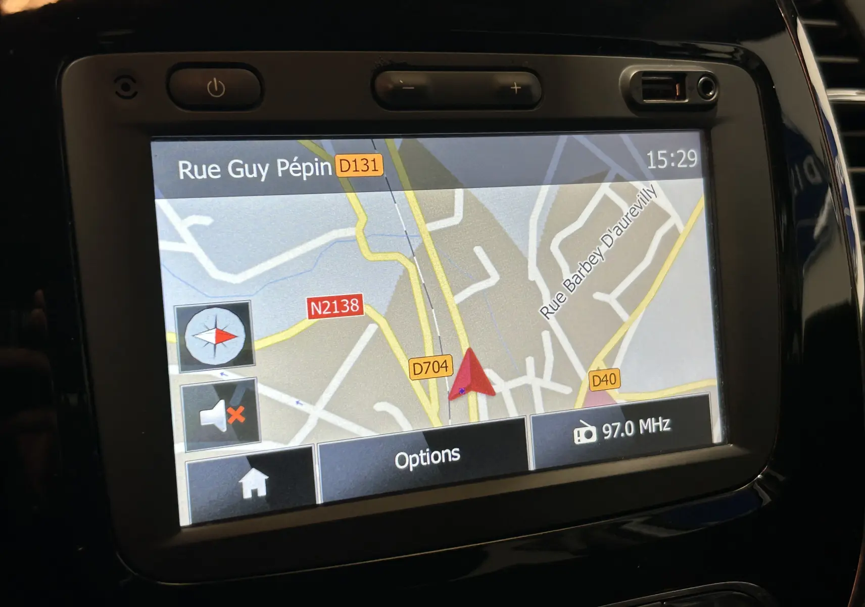 Écran GPS tactile du tableau de bord du Renault Captur gris, affichant une carte routière et la fréquence radio 97.0 MHz.