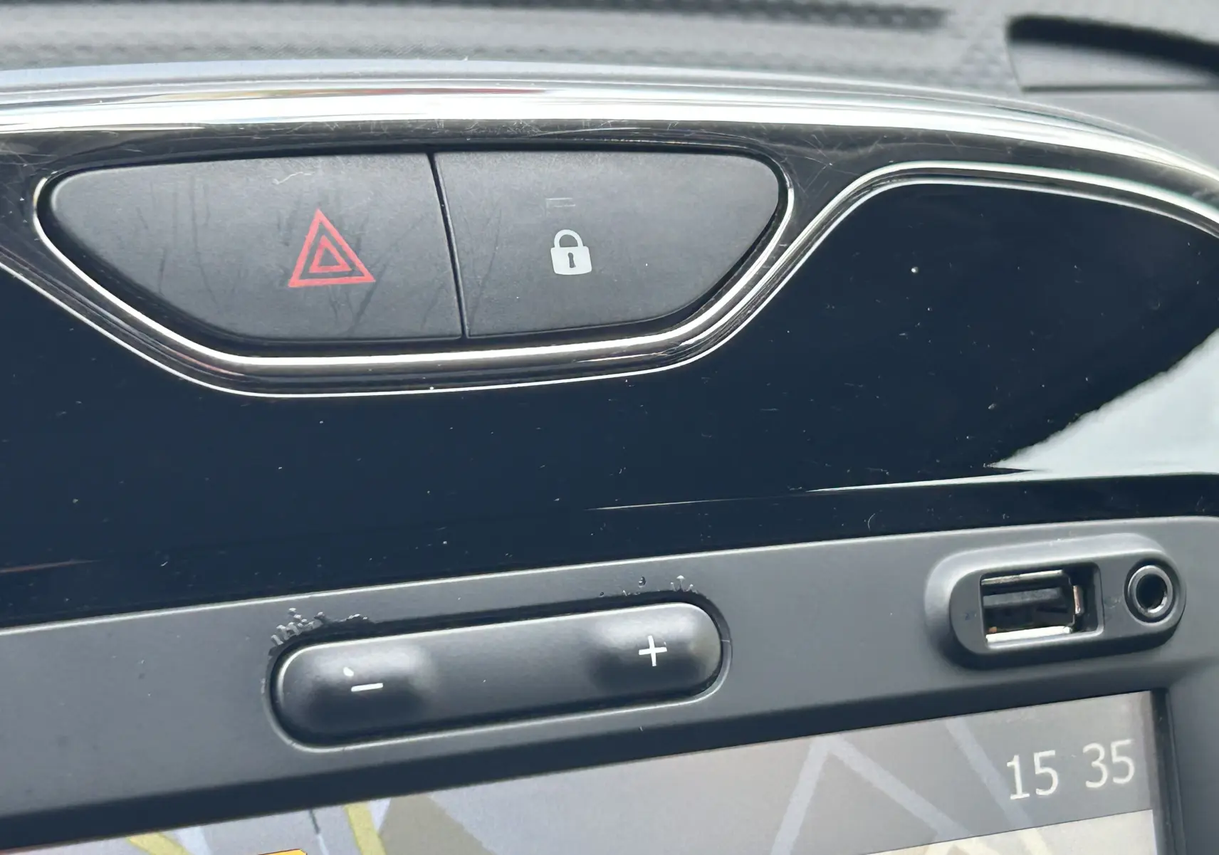 Gros plan sur la console centrale du Renault Captur gris montrant les boutons de verrouillage, d'alerte et la connectique USB avec GPS intégré.
